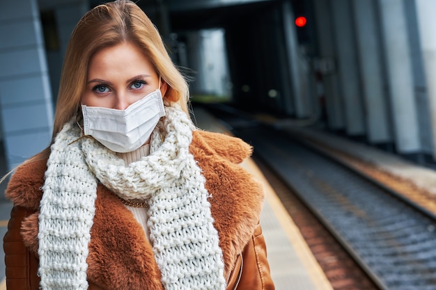 femme adulte à la gare portant des masques en raison des restrictions de covid-19