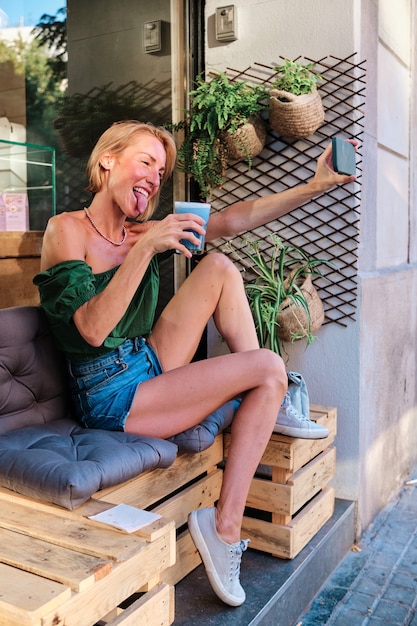 Une femme adulte heureuse faisant semblant avec une boisson saine et un smartphone