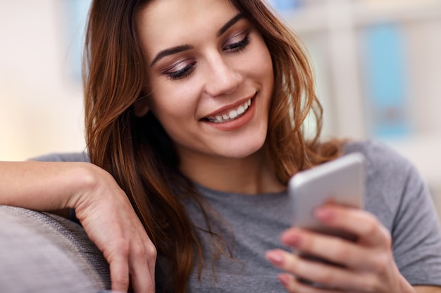 femme adulte heureuse utilisant le téléphone à la maison dans le salon