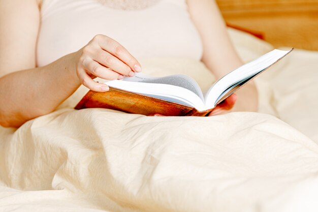 Femme adulte lisant un livre dans le lit. Temps de repos