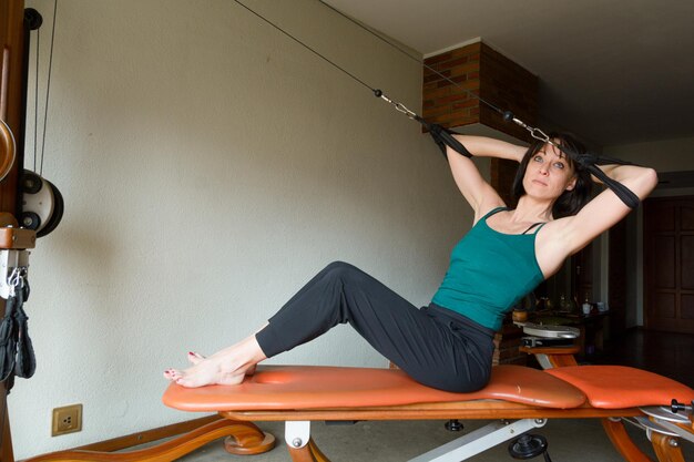 femme adulte à la maison entraînant les muscles du haut du corps sur une machine d'exercice