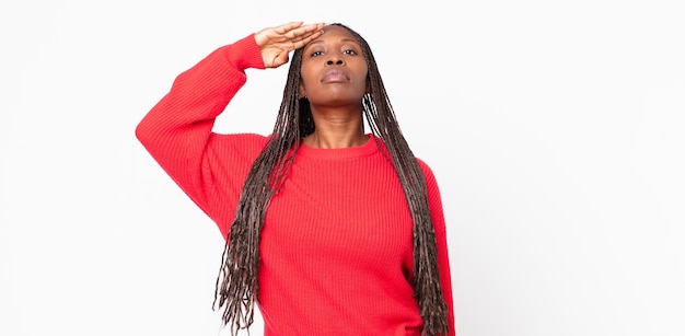 Femme adulte noire afro saluant la caméra avec un salut militaire dans un acte d'honneur et de patriotisme, montrant du respect