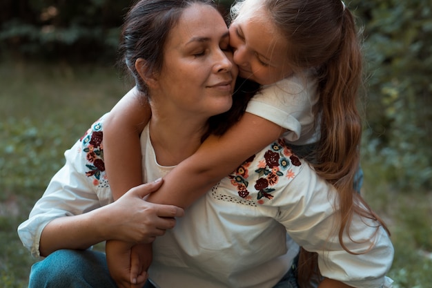 Femme adulte et petite fille mère et sa fille s'embrassant dans un parc ou une forêt