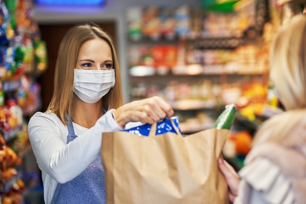 femme adulte portant un masque médical récupérant une commande en ligne à l'épicerie