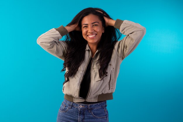 Femme adulte portant une veste décontractée faisant des expressions faciales en photo de studio avec fond bleu