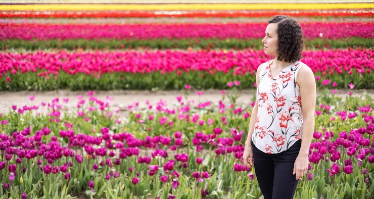 Photo femme adulte de race blanche regardant des fleurs de tulipes fraîches dans un champ