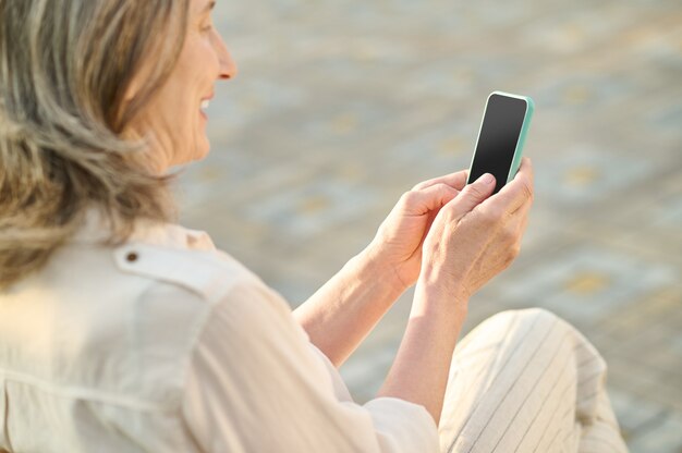 Femme adulte regardant l'écran du smartphone avec intérêt