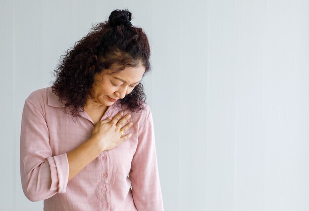 La femme adulte ressent de la douleur et utilise le toucher et la prise de la main sur la poitrine affectée par l'insuffisance cardiaque congestive ou la réanimation cardio-pulmonaire.