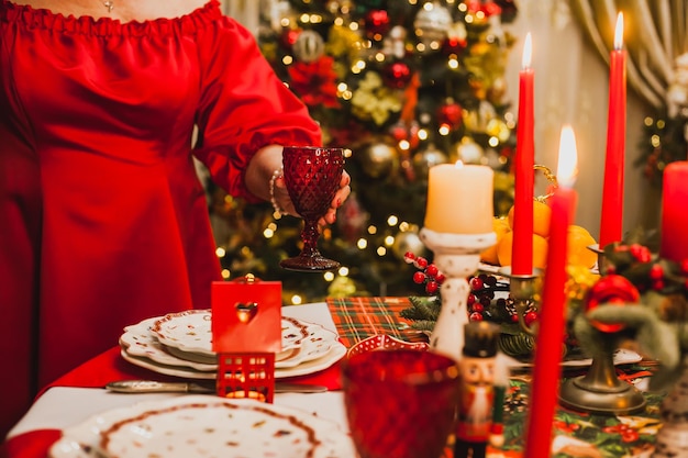 Une femme adulte en robe rouge fait un service de Noël à la maison