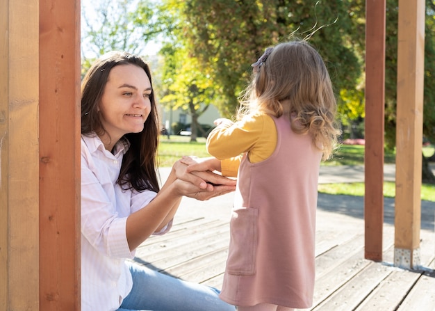 Femme adulte s'amusant avec sa fille enfant dans un parc verdoyant.