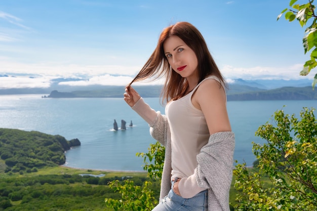 Femme adulte en T-shirt léger debout sur le rivage de la montagne contre une vue panoramique sur la mer le jour d'été