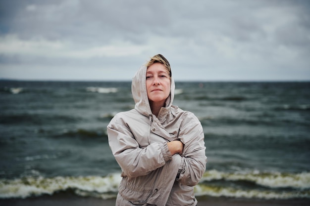 Femme adulte en veste debout près de la mer