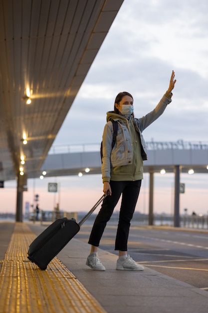 Femme à l'aéroport attrapant un taxi hélant un taxi à l'arrivée et au départ de l'aéroport