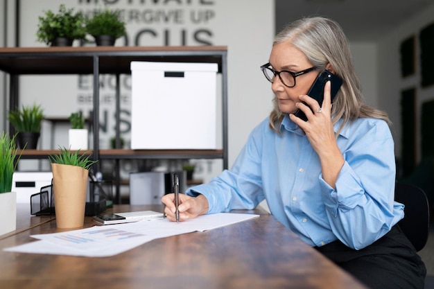 Femme d'affaires adulte travaillant au bureau parlant sur la gestion des taxes sur les factures d'entreprise de téléphone portable