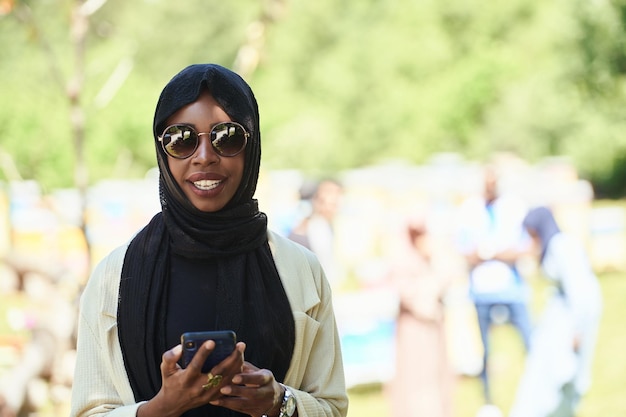 femme d'affaires africaine utilisant un téléphone intelligent portant des vêtements islamiques traditionnels