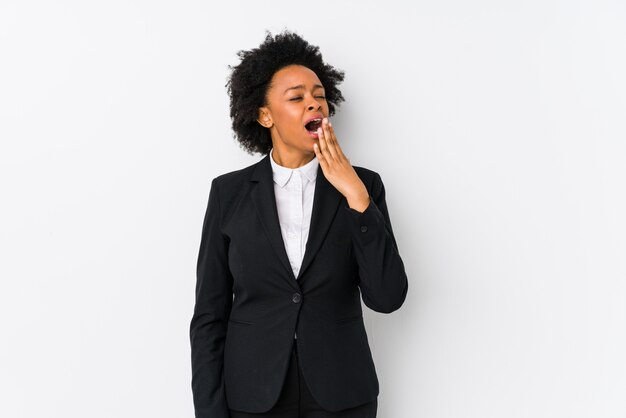 Femme d'affaires afro-américaine d'âge moyen contre un mur blanc bâillant montrant un geste fatigué couvrant la bouche avec la main.