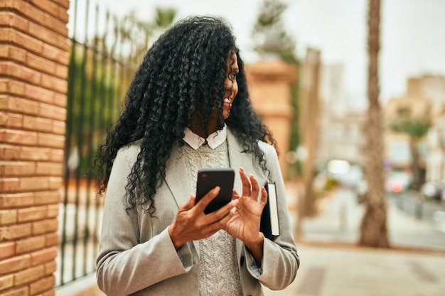 Femme d'affaires afro-américaine d'âge moyen utilisant un smartphone dans la ville