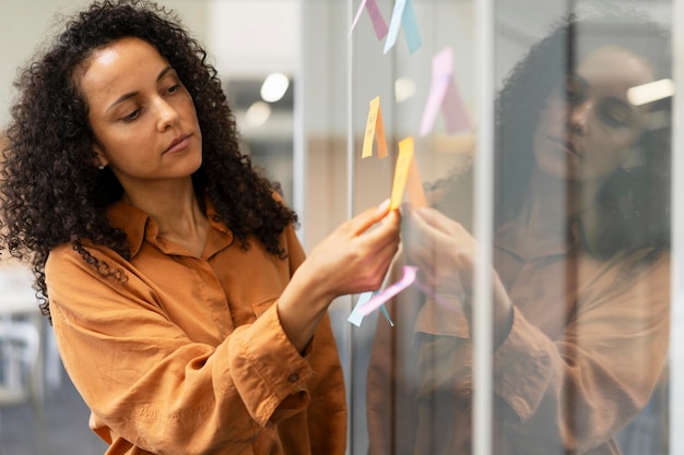 Femme d'affaires afro-américaine attrayante utilisant des notes autocollantes travaillant dans le concept Scrum moderne