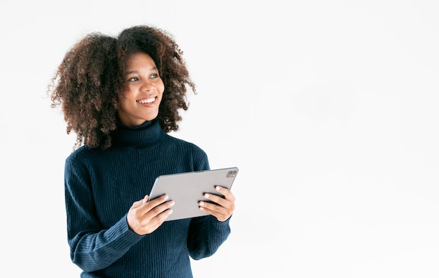 Une femme d'affaires afro-américaine heureuse utilisant une tablette numérique sur un fond clair pour copier de l'espace