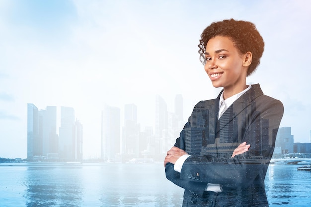 Femme d'affaires afro-américaine noire souriante en costume dans les bras croisés pose le paysage urbain de Singapour Le concept de femme dans les affaires Fonds d'investissement Double exposition