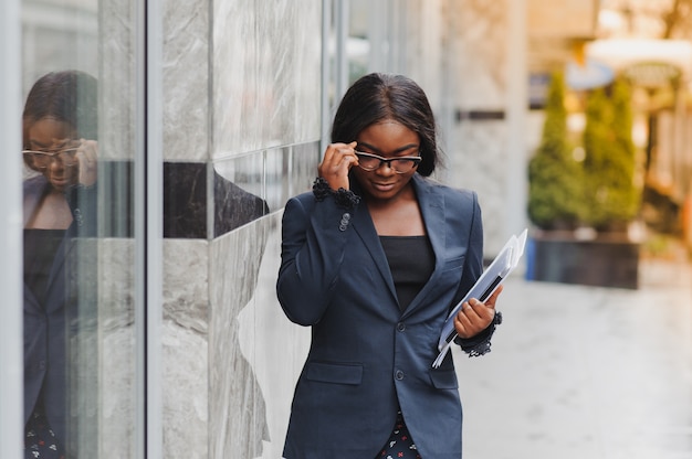 Femme d'affaires afro-américaine parlant sur un téléphone portable près d'un immeuble de bureaux