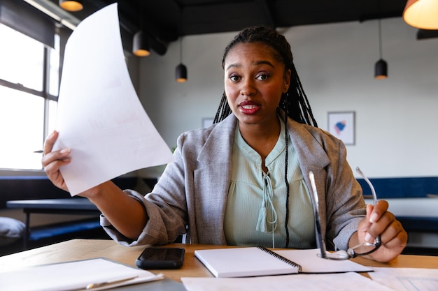 Une femme d'affaires afro-américaine de taille plus grande faisant un appel vidéo au bureau. Bureau occasionnel, affaires, professionnel, communication et travail, inchangé.