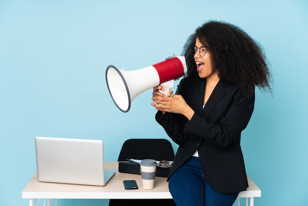 Femme d'affaires afro-américaine travaillant dans son lieu de travail en criant à travers un mégaphone