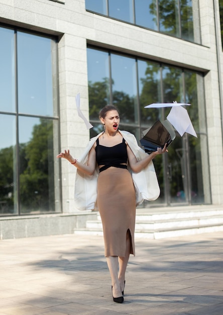 Une femme d'affaires agacée étale des feuilles de documents en ville