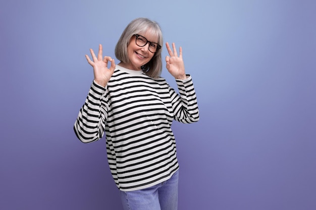 Femme d'affaires d'âge moyen aux cheveux gris posant joyeusement sur un fond de studio lumineux