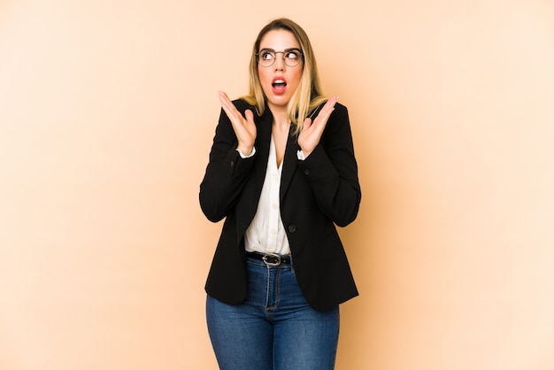 Femme d'affaires d'âge moyen isolée sur beige surpris et choqué.