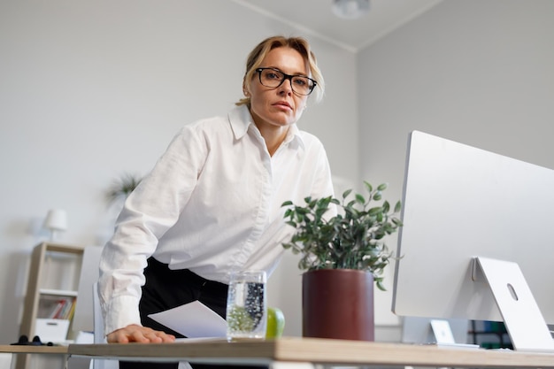 Femme d'affaires d'âge moyen sérieuse insatisfaite au bureau regardant avec colère la caméra