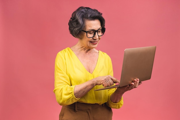 Femme d'affaires âgée âgée avec ordinateur portable Grand-mère isolée sur fond rose