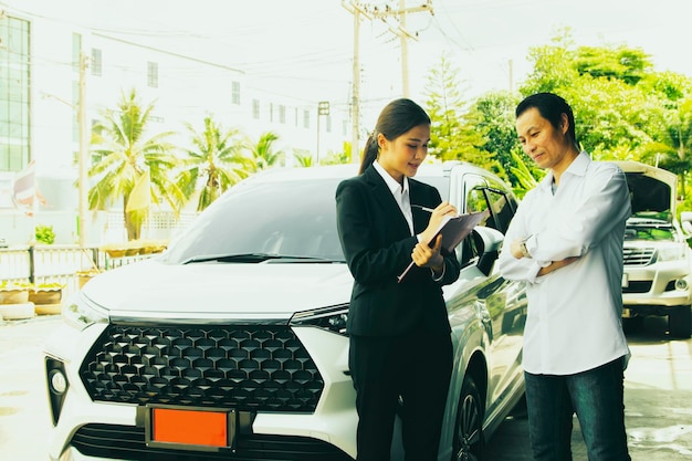 Une femme d'affaires agent d'assurance automobile contracte un nouveau propriétaire de voiture avec un homme avec un panneau rouge pour la sécurité.
