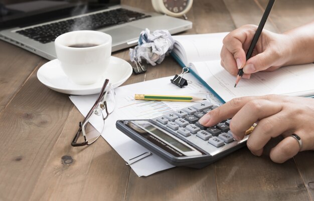 femme d&#39;affaires à l&#39;aide de la calculatrice avec café chaud et ordinateur