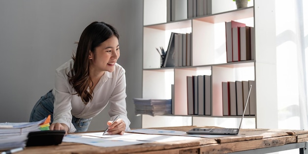 Femme d'affaires à l'aide d'une calculatrice pour faire des finances mathématiques sur un bureau en bois dans le bureau et les statistiques de comptabilité fiscale de fond de travail d'affaires et le concept de recherche analytiquex9