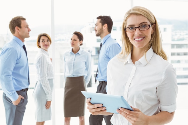 Femme d&#39;affaires à l&#39;aide de tablette numérique avec des collègues derrière