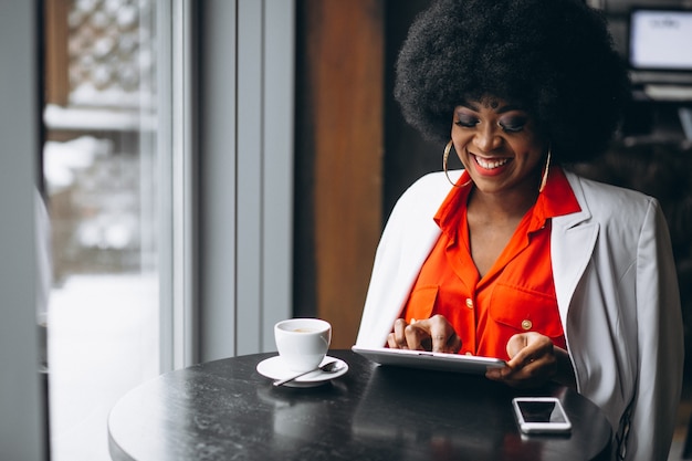 Femme d&#39;affaires américaine afro avec tablette et café dans un café