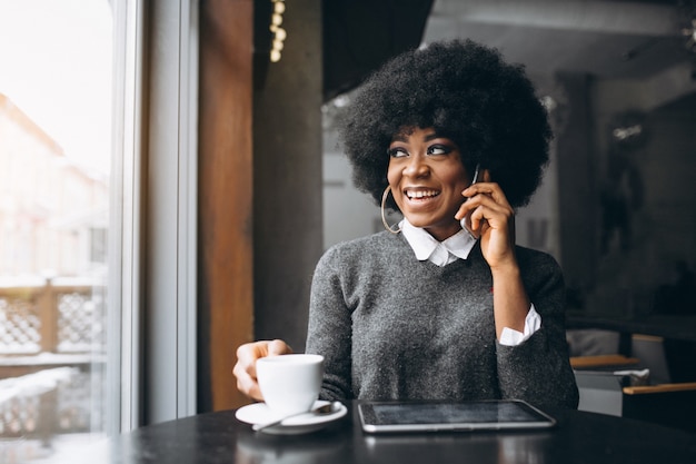 Femme d&#39;affaires américaine afro avec tablette et café dans un café