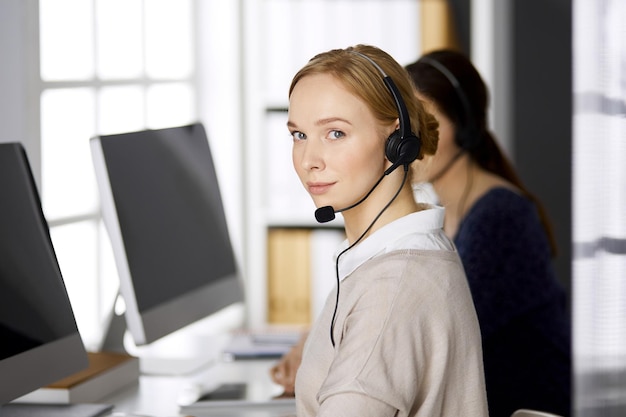 Une femme d'affaires amicale qui parle par casque alors qu'elle est assise au bureau.