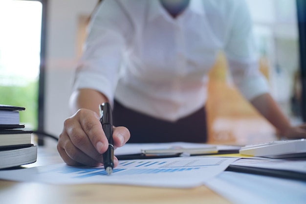 Une femme d'affaires analyse des graphiques à table dans son bureau.