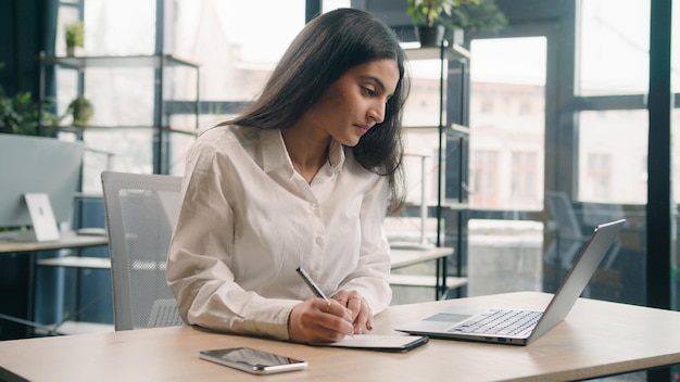 Femme d'affaires arabe fille indienne femme d'affaires gestionnaire ordinateur portable travail écrire des notes de cahier