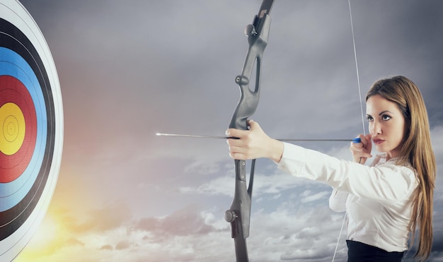 Femme d'affaires avec arc et flèche pointant vers le centre de la cible