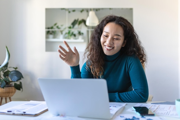 Femme d'affaires asiatique en appel vidéo assise à son bureauPhoto recadrée d'une jeune femme séduisante utilisant son ordinateur portable pour passer un appel vidéo à la maison