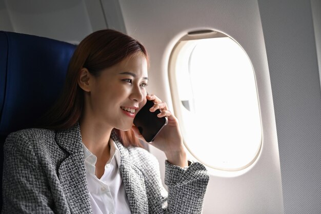 Femme d'affaires asiatique confiante au téléphone lors d'un voyage d'affaires dans une autre ville en avion