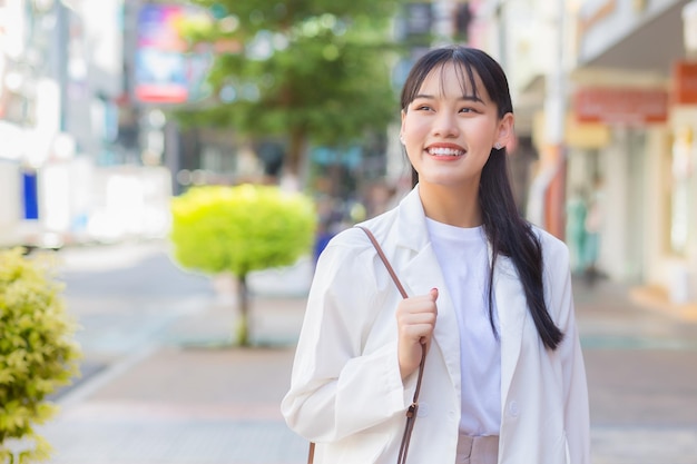 Femme d'affaires asiatique confiante qui porte une chemise blanche pendant qu'elle marche pour travailler au bureau.