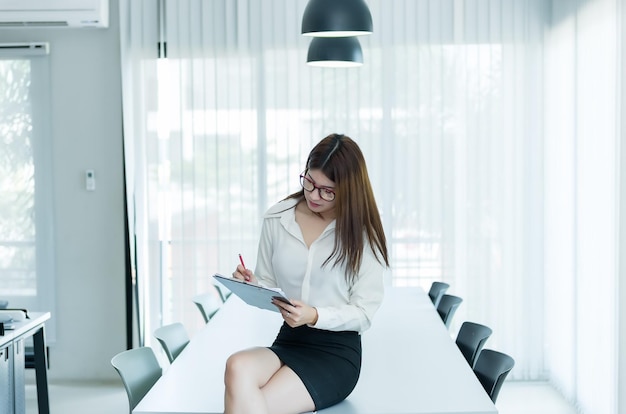 Femme d'affaires asiatique Écrire un document sur le bureauTravailler sur le lieu de travailThaïlandais