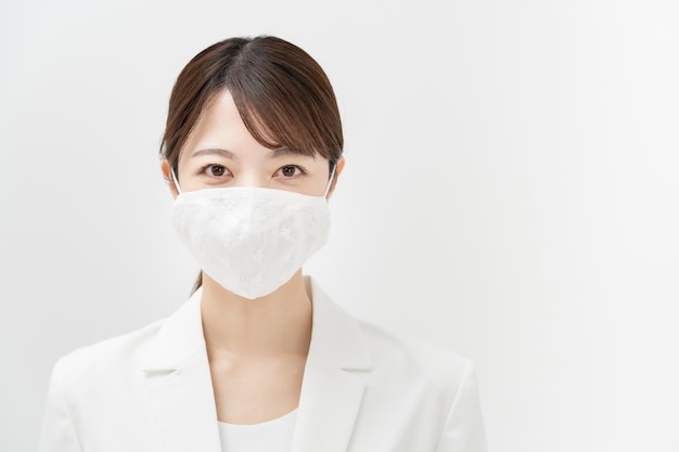 Femme d'affaires asiatique dans un costume blanc portant un masque