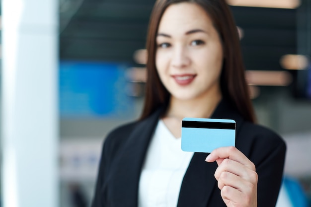 Femme d'affaires asiatique détenant une carte de crédit vierge. Portrait de belle fille au bureau ou salle de réunion