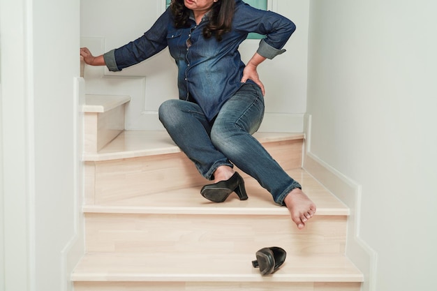 Femme d'affaires asiatique douleur cheville pied avec crampe à la jambe et tomber dans les escaliers parce que les surfaces glissantes au bureau