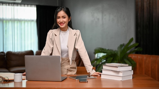 Une femme d'affaires asiatique du millénaire confiante et prospère se tient à son bureau